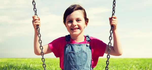 Happy little girl swinging on swing outdoors — Stock Photo, Image