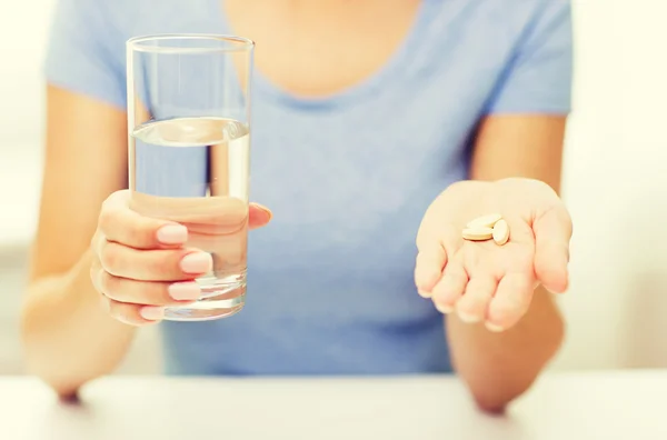 Primer plano de las manos de la mujer con pastillas y agua — Foto de Stock