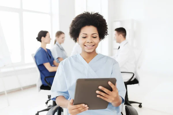 Enfermera feliz con la tableta PC sobre el equipo en el hospital — Foto de Stock
