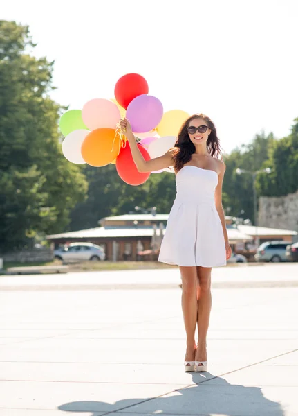 Gülümseyen güneş gözlüğü balonlarla genç kadın — Stok fotoğraf