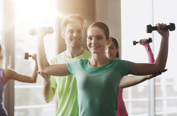 Glückliche Frauen und Trainer mit Kurzhanteln im Fitnessstudio — Stockfoto