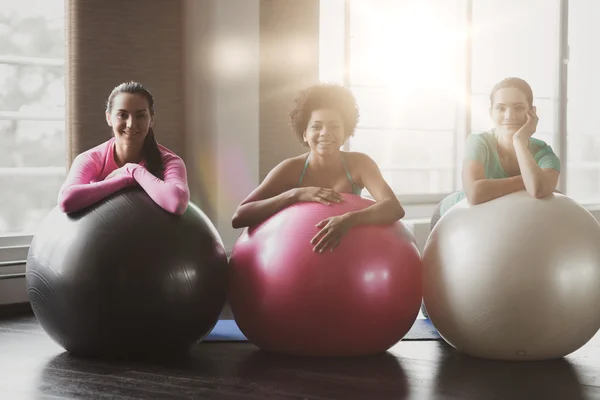 Grupo de mulheres sorridentes com bolas de exercício no ginásio — Fotografia de Stock