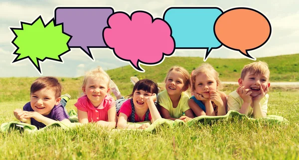 Group of kids lying on blanket or cover outdoors — Stock Photo, Image