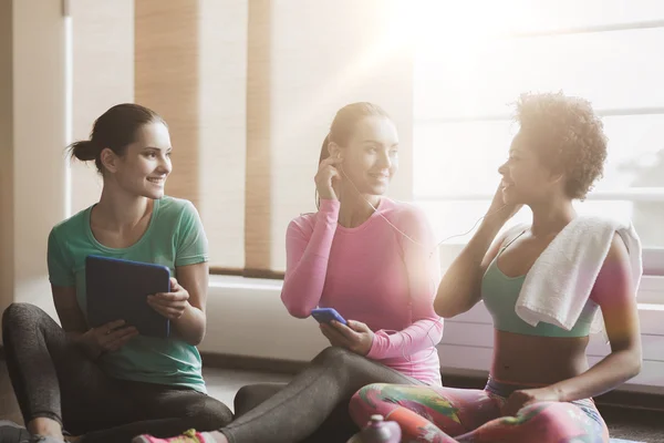 Gelukkig vrouwen luisteren naar muziek in de sportschool — Stockfoto