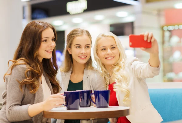 Mujeres jóvenes sonrientes con tazas y teléfono inteligente —  Fotos de Stock