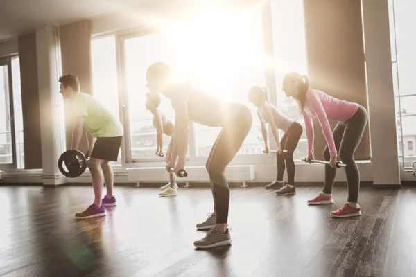 Grupo de personas haciendo ejercicio con barra de pesas en el gimnasio — Foto de Stock