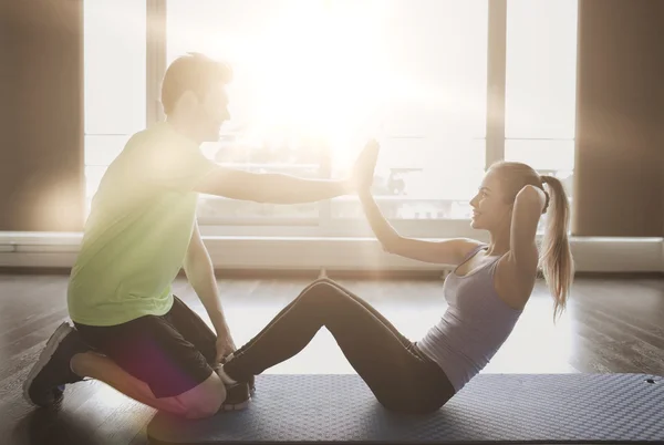 Kvinna med personlig tränare gör sit ups i gym — Stockfoto