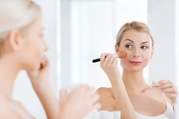 Женщина с щеткой для макияжа и порошком в ванной комнате — стоковое фото