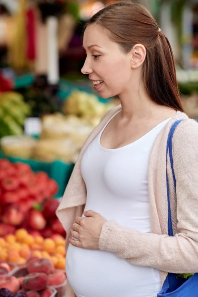 Беременная женщина выбирает еду на рынке — стоковое фото