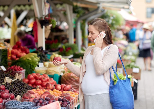 Pregnant woman calling on smartphone at market — Stock Photo, Image