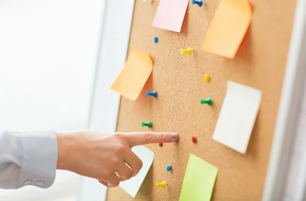 Hand pointing to cork board with stickers and pins — Stock Photo, Image