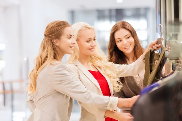Gelukkig jonge vrouwen kiezen kleren in winkelcentrum — Stockfoto