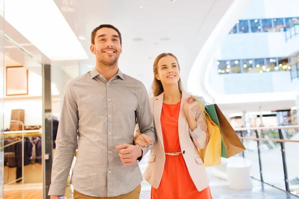 Lyckligt ungt par med shoppingväskor i köpcentret — Stockfoto