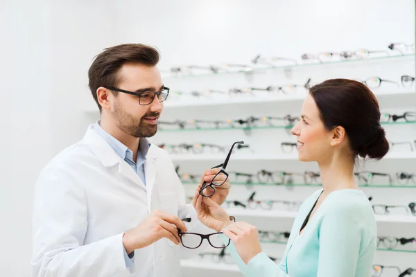 Žena a ukazující brýle v obchodě optika optik — Stock fotografie