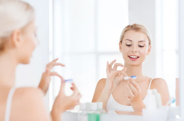 Ung kvinna sätter på kontaktlinser på badrum — Stockfoto
