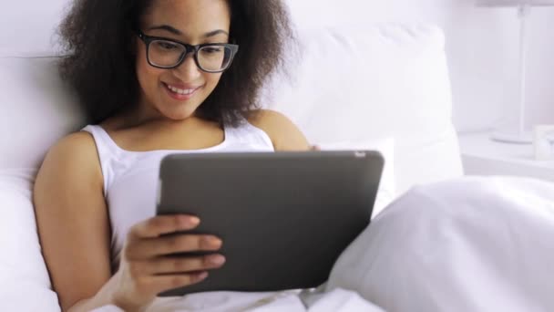 African woman with tablet pc in bed at home — Stock Video