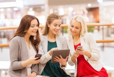 happy women with smartphones and tablet pc in mall clipart