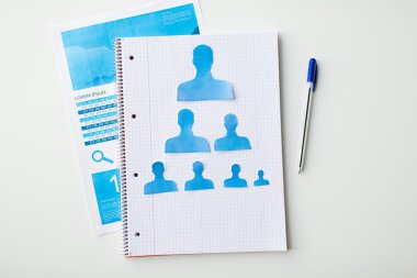 close up of paper human shapes on notebook clipart