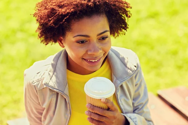 Smiling african woman drinking coffee outdoors — Stock Photo, Image