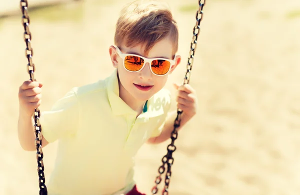 Glad liten pojke svängande på swing på lekplats — Stockfoto