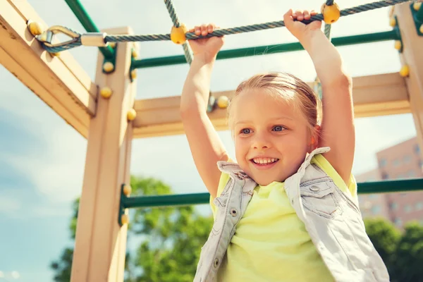 Fröhliches kleines Mädchen klettert auf Kinderspielplatz — Stockfoto