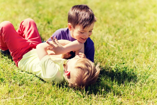 Šťastný malí kluci bojovat o zábavu na trávě — Stock fotografie