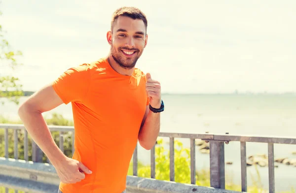 Sonriente joven corriendo en verano junto al mar —  Fotos de Stock