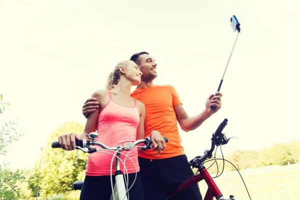 Пара з велосипедом і смартфоном selfie stick — стокове фото