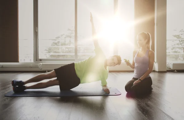 Hombre y mujer haciendo ejercicio de tablón en la estera en el gimnasio — Foto de Stock