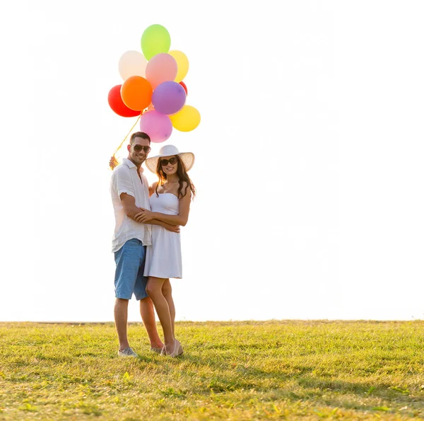 Усміхнена пара з повітряними кульками на відкритому повітрі — стокове фото