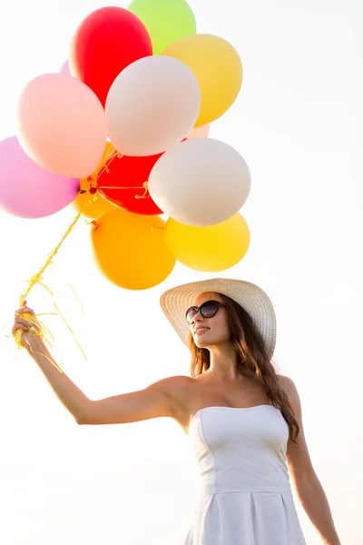 Gülümseyen güneş gözlüğü balonlarla genç kadın — Stok fotoğraf