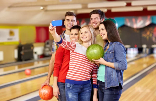 Glada vänner med smartphone i bowling club — Stockfoto