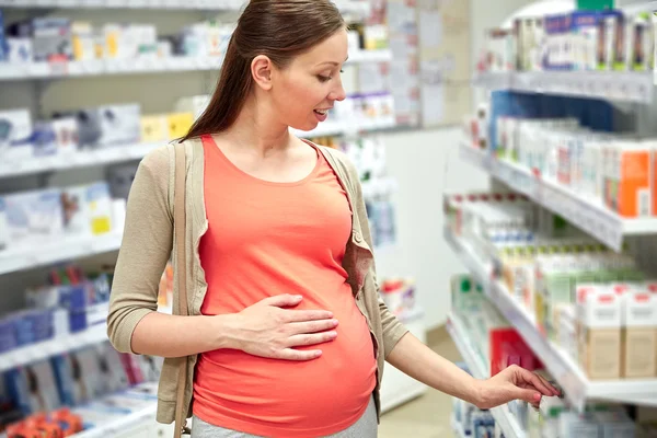 Mujer embarazada feliz elegir la medicina en la farmacia —  Fotos de Stock