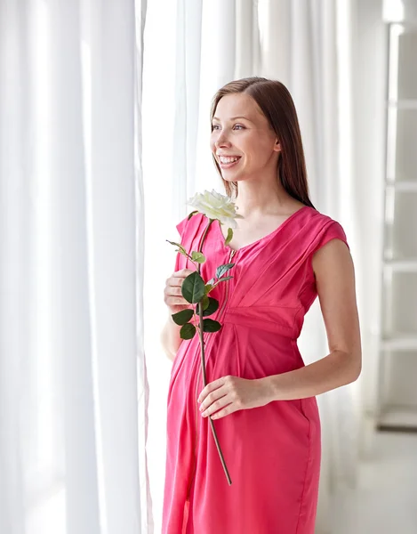 Mulher grávida feliz com flor de rosa em casa — Fotografia de Stock