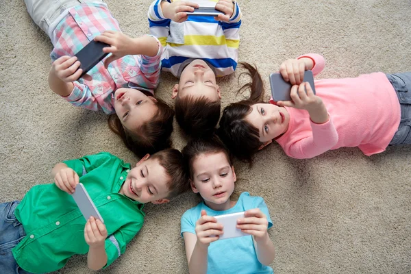 Enfants heureux avec smartphones couchés sur le sol — Photo