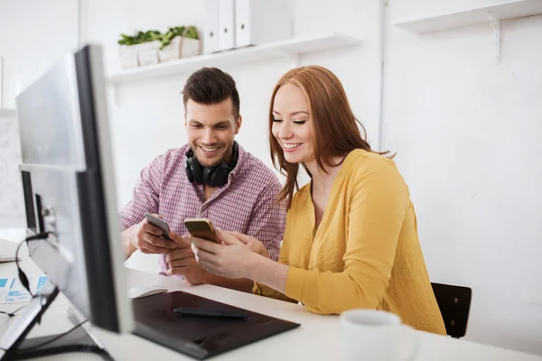 Équipe créative heureuse avec smartphones au bureau — Photo