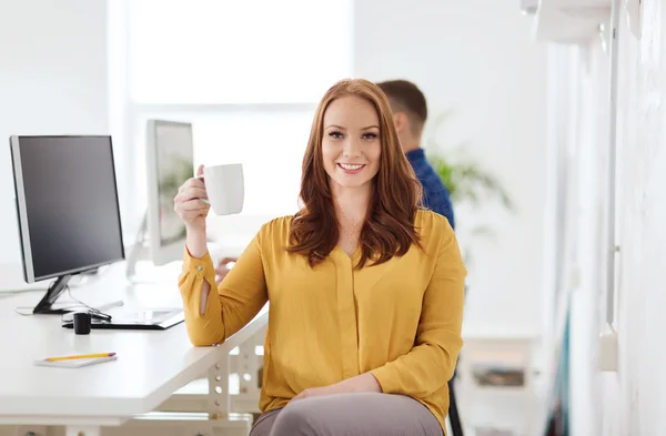 Glückliche Frau, die Kaffee oder Tee im Büro trinkt — Stockfoto