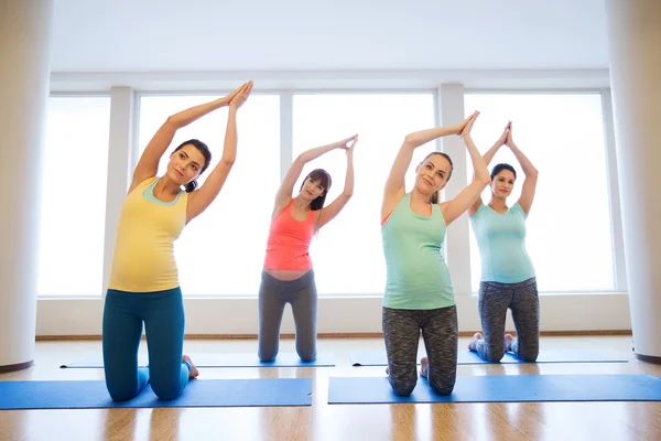 Mujeres embarazadas felices haciendo ejercicio sobre alfombras en el gimnasio — Foto de Stock