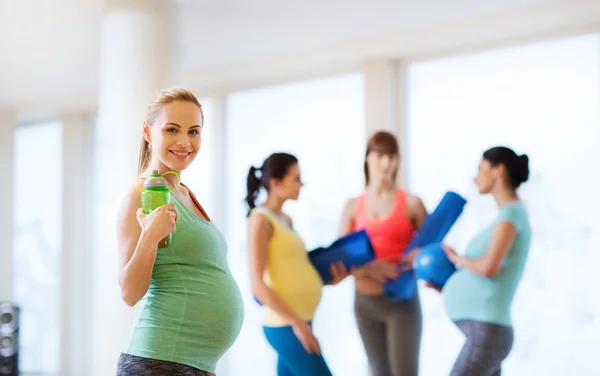 Mujer embarazada feliz con botella de agua en el gimnasio — Foto de Stock