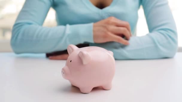 Mujer poniendo una moneda de euro en alcancía — Vídeos de Stock