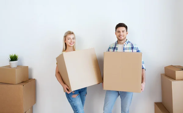 Улыбающаяся пара с большими коробками, переезжающими в новый дом — стоковое фото
