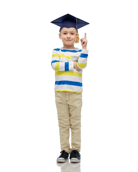 Happy boy in bachelor hat pointing finger up — Stock Photo, Image