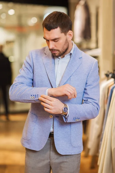Joven hombre tratando de chaqueta en tienda de ropa — Foto de Stock