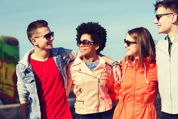 Happy teenage friends in shades talking on street — Stock Photo, Image