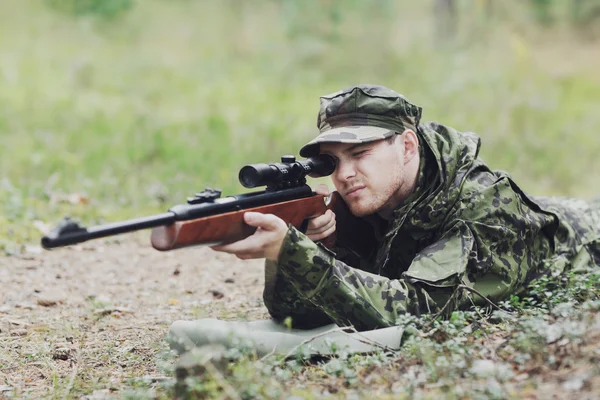 Young soldier or hunter with gun in forest — Stock Photo, Image