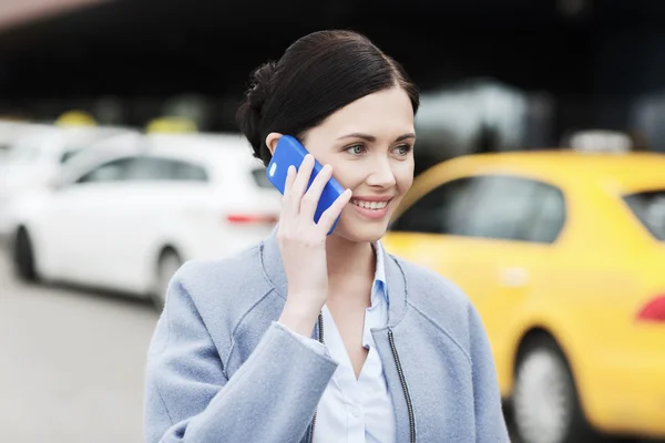 Lächelnde Frau mit Smartphone über Taxi in der Stadt — Stockfoto