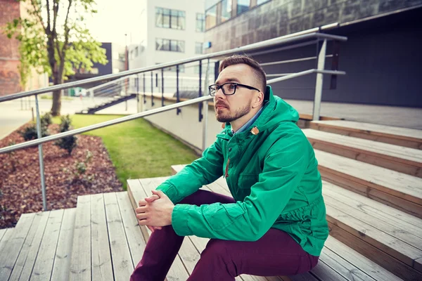 Feliz jovem hipster homem sentado em escadas na cidade — Fotografia de Stock