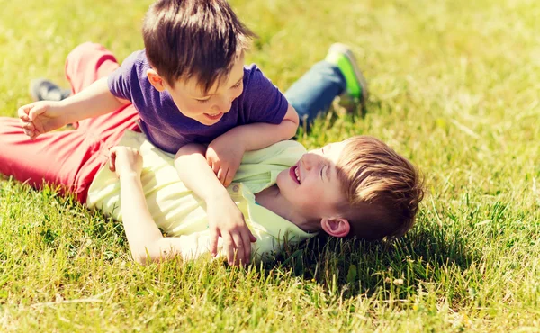 Niños pequeños felices luchando por diversión en la hierba — Foto de Stock