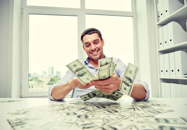 Homem de negócios feliz com montão de dinheiro no escritório — Fotografia de Stock