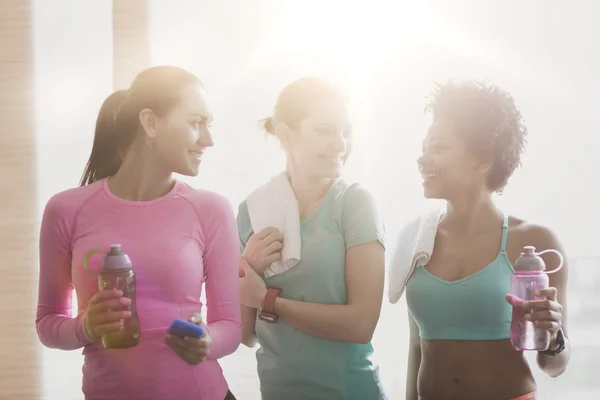 Happy women with bottles of water in gym — Stock Photo, Image